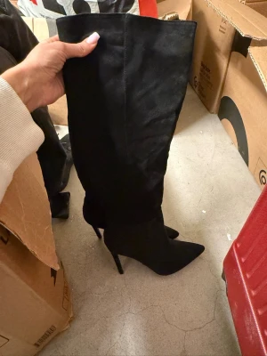 Svarta overknee stövlar med klack - Säljer ett par svarta overknee stövlar med spetsig tå och hög smal klack. Stövlarna är i mockaimitation och hög klack. Aldrig använda 