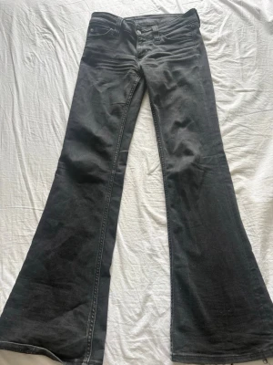 Svarta bootcut jeans med utsvängda ben - Säljer ett par svarta bootcut jeans med riktigt utsvängda ben och klassisk femficksmodell. Jeansen har hög midja och är sydda i ett mjukt denimtyg. Perfekta för dig som gillar retrovibbar och vill sticka ut med din stil.