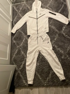 Nike tech ställ vit (old gen) - Säljer mitt Nike tech set (tröja och byxor) det är i bra skick förutom en liten fläck på vänster arm (finns bild)  