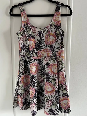 H&M klänning i färgglatt mönster.  - Klassisk klockad H&M klänning med ett färgglatt blommönster i strl 38. Bortklippt lapp. 