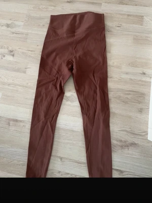 Bruna ribbade tights från MKLifestyle - Snygga bruna tights från MKLifestyle i ribbat material. Tillverkade av 74% nylon och 26% spandex för en stretchig och bekväm passform. Höga i midjan och perfekta för träning eller chill. Stilsäker look för gymmet eller vardagsoutfiten.