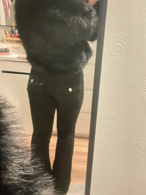 Svarta bootcut jeans med silverknappar - Säljer ett par svarta bootcut jeans med silverfärgade knappar på bakfickorna. Jeansen har klassisk femficksdesign och är tillverkade i ett stretchigt material som sitter snyggt. Perfekta för dig som gillar en tidlös och clean look. Pris kan diskuteras 