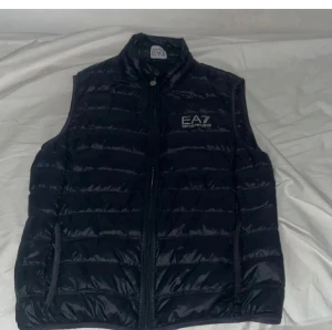 Marinblå  väst från EA7 Emporio Armani - Snygg marinblå  dunväst från EA7 Emporio Armani Västen har två sidofickor med dragkedja och diskret logga på bröstet. Jag har använt den ett par gånger men det är inget fel på den.