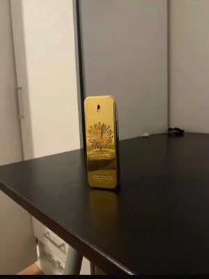 Paco Rabanne 1 Million Parfym - Säljer en ikonisk Paco Rabanne 1 Million parfym i en snygg guldig och svart rektangulär flaska. Flaskan har en metallisk guldfärgad framsida med präglad logga och detaljer, samt svart baksida. Perfekt för dig som gillar lyxiga och unika dofter. ca 50ml kvar.
