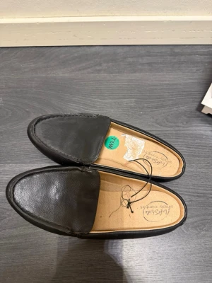 Svarta loafers i skinn från Lakeside - Stilrena svarta loafers från Lakeside i mjukt skinn med klassisk design och rundad tå. Skorna har en enkel ovandel utan dekorationer och en bekväm innersula med texten 'simply comfort'. Perfekta för dig som gillar en clean och tidlös look.