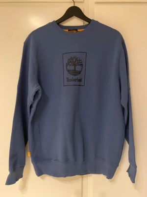 Blå sweatshirt från Timberland - Snygg blå sweatshirt från Timberland med klassiskt tryckt logotyp på bröstet.Perfekt för en avslappnad och stilren look.Den ser ny ut.