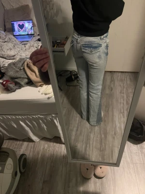 Ljusblå bootcut jeans med låg midja - Säljer ett par ljusblå jens med en mörkblå slitt på sidan dom passar perfekt och jag är 160 och de är perfekt längd.