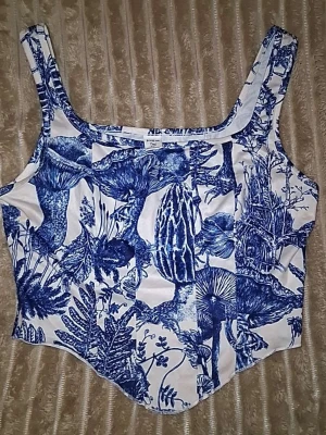 Vit och blå korsettopp från SHEIN - Säljer en snygg korsettopp från SHEIN i vitt med blått botaniskt mönster. Toppen har breda axelband och markerad midja för en trendig siluett. Perfekt att styla med jeans eller kjol för en cool look.