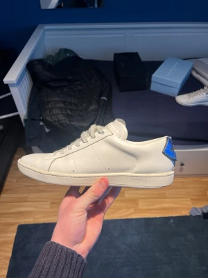 Saint Laurent skor  - Säljer ett par nästan HELT NYA, saint lauren skor | storlek 41 | färg vita med blå och röd detalj vid hälen | skick 9/10 | NY PRIS 6500kr Mitt pris 1299🤩🤩🤩. Bara att skriva för eventuella frågor. 