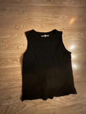 Svart ärmlös topp Hampton Republic - Snygg svart ärmlös topp från Hampton Republic. Enkel och stilren design med rund halsringning. Perfekt att matcha med jeans eller kjol för en clean look. Tillverkad i mjukt bomullsmaterial som känns skönt mot huden.