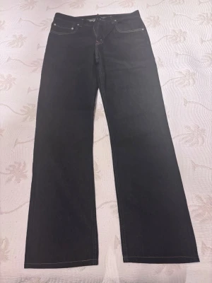 Svarta raka jeans från Levi's - Snygga oanvända mörkblåa jeans från Levi's med rak passform och klassiska fem fickor. Jeansen har kontrastsömmar och Levi's ikoniska läderpatch bak i midjan. Tillverkade i slitstark denim som passar perfekt till en avslappnad stil.