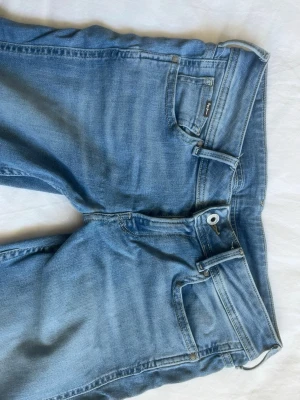 Ljusblå jeans från Pepe Jeans - Säljer ett par ljusblå jeans från Pepe Jeans med klassisk femficksmodell och låg midja. Jeansen har en snygg tvätt och utsvängda ben. Materialet är mjukt denim med lite stretch för extra komfort. Perfekta till en avslappnad look.