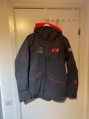 Helly Hansen skidjacka - Mörkblå Helly Hansen skidjacka. Storlek L dam. Passar även herr M. Mycket fint skick. Många bra fickor för förvaring samt en ficka i armen för liftkort. Jackan är tunt fodrad och har även ventilations fickor i armhålorna. Vid föer frågor hör gärna av dig! Mvh Moltas.