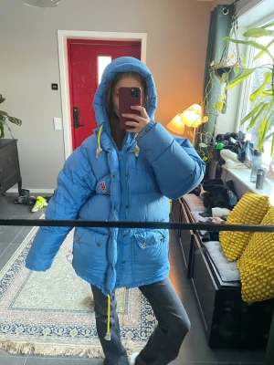 Blå dunjacka från Fjällräven XXS - Säljer en blå, oversized dunjacka från Fjällräven i storlek XXS. Knappt använd, har precis kemtvättat jackan. Skulle säga att den passar XS/M. De vita ”lapparna” på snöret är lite förstörda men inget som syns på lång håll. Ny pris 9 999kr