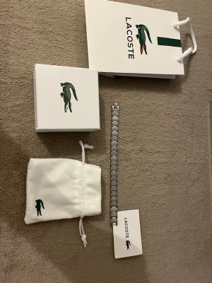 Lacoste armband  - Jätte fint Lacoste armband kommer med box och allt kan ändra storlek om man går till en juvelerare. 