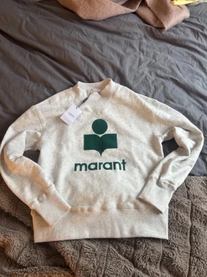  Isabel Marant tröja - Snygg grå sweatshirt från Isabel Marant  med grönt tryck och logga framtill. Skitsnygg och jätte popoulät. Prislapp finns kvar. Pris kan diskuteras vid snabb affär💕💕