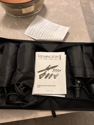 Remington Multistyler S8670 set - Remington Multistyler S8670 är ett svart stylingverktyg med flera utbytbara tillbehör för olika frisyrer. Setet innehåller locktång, plattång, borste och olika stylinghuvuden, allt i en praktisk svart väska. Perfekt för dig som vill variera din look enkelt. Har endast två av hårklämmorna kvar. Endast plattångs tillbehöret har använts typ 2 gånger.