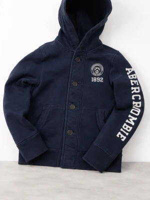 Marinblå Cardigan från Abercrombie & Fitch - Mörkblå hoodie från Abercrombie & Fitch med stor huva, knappar framtill och tryck på ärmen samt bröstet. Snygg college-stil med fickor och ribbade muddar. Perfekt för en avslappnad look. Storlek S 
