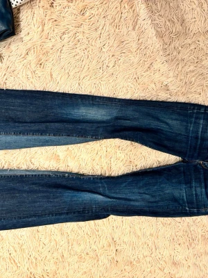 Mörkblå jeans från Citizens of Humanity - Snygga mörkblå jeans från Citizens of Humanity med klassisk femficksdesign och diskreta slitningar. Jeansen bootcut ben och är tillverkade i mjuk denim med lite stretch för extra komfort. Perfekta för en avslappnad och trendig look.