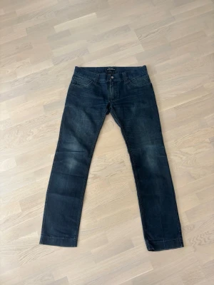 Mörkblå jeans från Dolce & Gabbana - Snygga mörkblå jeans från Dolce & Gabbana med raka ben och klassisk femficksdesign. Jeansen har diskreta slitningar och är tillverkade i denim med en autentisk tvätt. Perfekta för dig som gillar stilrena och tidlösa jeans. 48/104 i mått 48 i bredd o 104 i öängd 