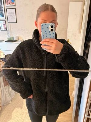 Teddy jacka - En svart trddyjacka i ganska tunt material då passar bra på våren och hösten. Lite längre i modellen och med hål för tummarna.