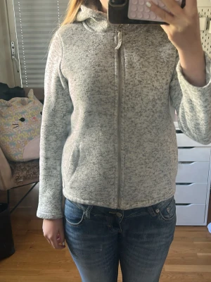 Ljusgrå ziphoodie med huva - Mysig ljusgrå ziphoodie med huva och fickor framtill. Jackan har en rak passform och är tillverkad i ett mjukt material som passar perfekt för kyligare dagar. Stängs med dragkedja hela vägen upp.
