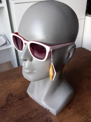 Vita cat eye solglasögon från Sunshine  - Snygga solglasögon i klassisk cat eye-modell från Sunshine. Bågarna är vita och glasen är mörka, vilket ger en cool retrovibe. Perfekta för att lyfta vilken outfit som helst med en trendig touch.