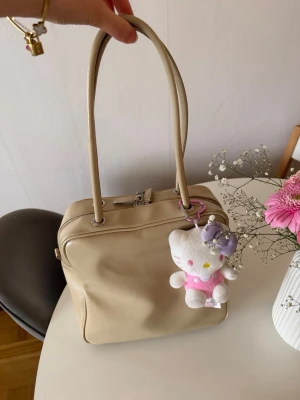 Beige handväska box - Stilren beige handväska i fyrkantig modell med långa handtag och dragkedja upptill.  Den är från Esprit. 