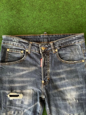 Dsquared2 jeans  - Storlek: W30 Längd: L30  ca 102 cm   Säljer ett par äkta Dsquared2 jeans i jättefint skick. Klassisk premium-denim med snygga, fabriksdesignade slitningar och en modern, slim fit passform. Jeansens tvätt ger en riktigt stilren och trendig look som passar både till vardag och fest.  ✔ Original Dsquared2 ✔ Fina slitningar (designade, ej överdrivna) ✔ Inga defekter – mycket gott skick ✔ Skön passform och hög kvalitet  Perfekta jeans för dig som vill ha något exclusivt GE MIG BUD!
