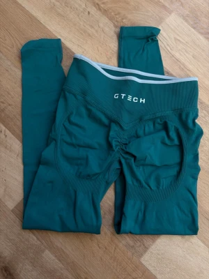 Align Seamless Scrunch Tights från Gtech - Säljer ett par turkosa seamless leggings från Gtech med hög midja och ribbad linning. Leggingsen har scrunch-detalj bak och är tillverkade i ett stretchigt material som sitter skönt på kroppen. Perfekta för träning eller chill.