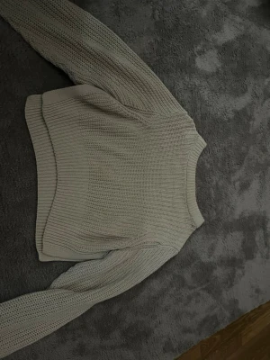 Beige stickad tröja Gina Tricot - Säljer en beige stickad tröja från Gina Tricot i storlek XS. Tröjan har en croppad passform, rund halsringning och breda ribbade muddar. Perfekt för dig som gillar en enkel men trendig look.