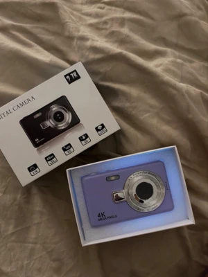 Lila digitalkamera 4K 27MP - Säljer en lila digitalkamera med 4K-upplösning och 27 megapixlar. Kameran har 16x zoom och en klassisk kompakt design med silverfärgad linsring. Perfekt för dig som vill ha en smidig kamera att ta med överallt. Levereras i originalkartong.