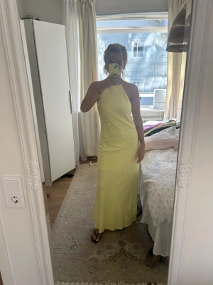 Ljusgul linneklänning  - Snygg ljusgul långklänning med smala axelband och halterneck. Klänningen har en elegant, figurnära passform och är ärmlös. Den är i linnebomulls blandning. Nyskick! 💛
