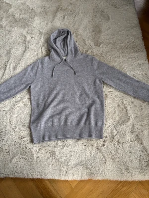 Cashmere tröja - Snygg grå hoodie från saylles i ett supermjukt och lyxigt material. Klassisk modell med huva och dragsnören, samt ribbade muddar vid ärmslut och nederkant. Perfekt för en chill och stilren look.