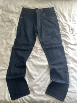 Mörkblå raka jeans från emilio - Snygga mörkblå jeans från emilo med klassisk rak passform och kontrastsömmar. Jeansen har fem fickor och är tillverkade i kraftig denim. Perfekta för dig som gillar en stilren och tidlös look.