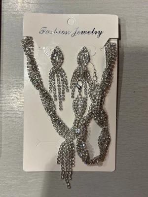 Set med glittrande strassmycken - Säljer ett set med matchande halsband och örhängen i silverfärg. Perfekt till Balen.