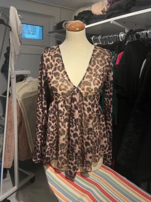 Leopardmönstrad mesh blus - Trendig blus i mesh med leopardmönster och djup v-ringning. Långärmad modell med lös passform och lätt transparent material. Perfekt för dig som vill sticka ut med en edgy och cool look.