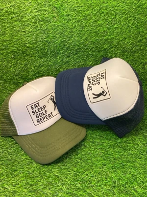 Truckerkepsar med golfmotiv - Två coola truckerkepsar med texten 'EAT SLEEP GOLF REPEAT' framtill. En keps är olivgrön med vit front och den andra är marinblå med vit front. Båda har mesh på baksidan och böjd skärm. Perfekt accessoar för golfälskare.