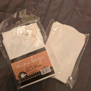 Vita mini papperspåsar 25-pack x 2 - Säljer 2 paket med 25 vita mini papperspåsar från Canvas Home Basics. Påsarna är 6,4 x 10,2 cm och perfekta för små presenter, pyssel eller förvaring av småsaker. Enkla och stilrena med vågig kant upptill.