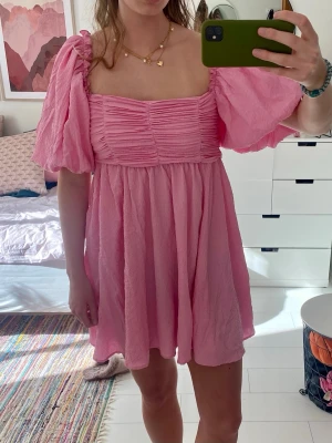 Rosa kortklänning - Söt rosa kortklänning med puffärmar och rynkade detaljer. Klänningen är helt ny och oanvänd! Jättefin o söt till sommaren!