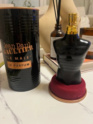 Jean Paul Gaultier Le Male Le Parfum 125ml - Jean Paul Gaultier Le Male Le Parfum i en snygg svart flaska formad som en manlig torso med gulddetaljer. Kommer i en svart och guldig metallburk. En ikonisk och lyxig herrdoft som sticker ut i badrumshyllan. HELT NY
