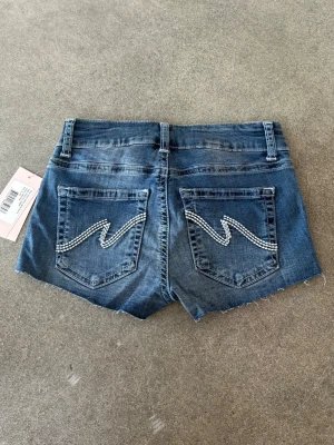 Blå lågmidjade jeansshorts - Snygga blå jeansshorts med låg midja från Nelly, storlek xs nya med prislappar kvar!