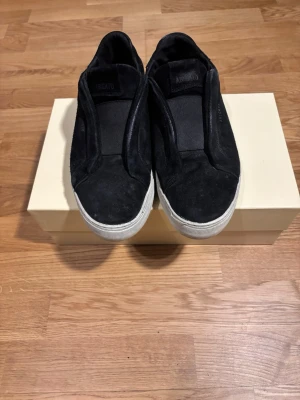 Axel Arigato 360 Sneakers – Svart Mocka - Säljer ett par stilrena och minimalistiska slip-on sneakers från Axel Arigato i svart mocka. En perfekt sko för dig som vill ha en sofistikerad men avslappnad look. Kvalitetshantverk som passar till allt från jeans till kostymbyxor. 