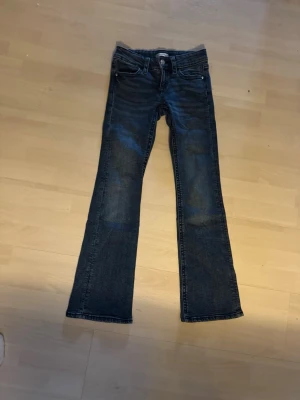 Mörkblå bootcut jeans - Snygga mörkblå bootcut jeans med klassisk femficksdesign och kontrastsömmar. Jeansen har lätt slitna detaljer på framsidan och bakfickor med lock och knapp. Perfekta för en avslappnad och trendig look. storlek 152