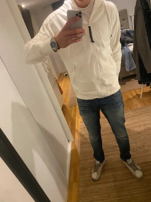 Vit hoodiejacka från C.P. Company - Snygg, stilren hoodie från CP Company med klassiska goggles designen.