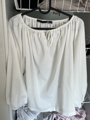 Vit offshoulder blus och samma i svart - Säljer en vit offshoulder blus med ballongärmar och knytning fram. Blusen har en luftig och avslappnad passform i ett lätt, strukturerat tyg. Perfekt för en trendig och enkel look. Och samma där med svart DEN VITA ÄR EX‼️OCH DEN SVARTA S‼️