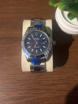Klocka - Stilren klocka med silverfärgat armband i metall och blå urtavla. Urtavlan har vita markeringar och en röd sekundvisare. Klassisk rund form och robust design som passar till många stilar. Priset kan diskuteras!