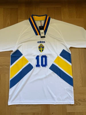 Dahlin #10 – Sverige 1994 Borta (storlek M) - Dahlin #10-tryck. Sverige 1994 Borta (vit). Storlek M. Helt ny och aldrig använd. Skickas snabbt 🚚💨  Mått (M): Halvt bröstmått 53 cm • Längd 74 cm • Ärmbredd 23 cm • Axelbredd 44 cm • Ärmlängd 40 cm • Manschett 19 cm.  🔥 Fan Edition – normal passform. 🇸🇪 Sverige landslag.  📩 Skicka gärna ett meddelande vid frågor eller prisförslag! 🛍 Bundle-rabatt upp till 20%! 📦 Skickas samma eller nästa dag.