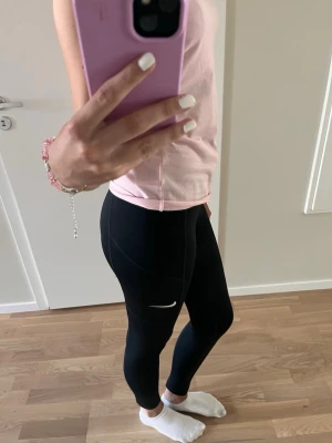 Svarta leggings från Nike - Säljer dessa svarta träningbyxorna från nike. perfekt till ett gympass eller idrotten. säljer då de blev lite för korta för mig som är 176cm lång. skulle säga att de är storlek xs-s💗 skriv om ni har frågor, priset kan diskuteras🫶🏻