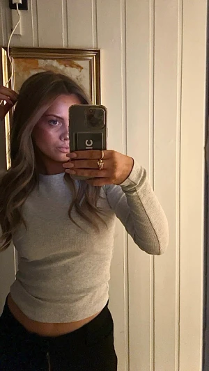 Ljusgrå ribbad långärmad topp - En enkel och stilren ljusgrå långärmad topp från Vero Moda. Toppen är ribbad och har en tight passform med rund halsringning. Perfekt att matcha med jeans eller kjol för en clean look. (Använd max 5 gånger)